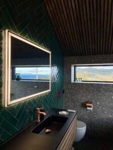 Svart nedsenket servant med kobberfarget kran og grønn herringbone-flis – servant og toalettsone i baderomsrenovering Naustmarka, Malvik